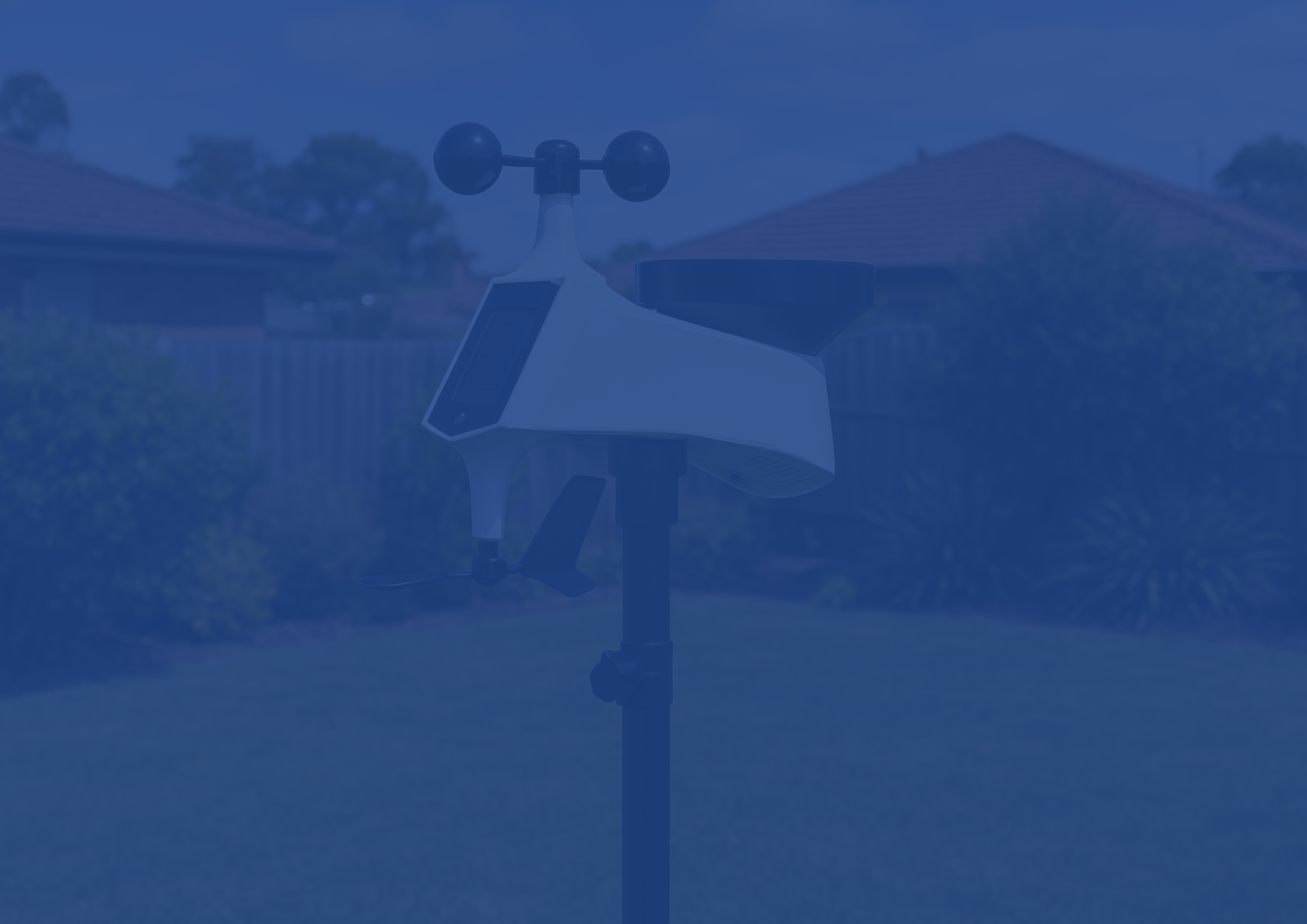 Anemometer on a stand with a blurred background of houses and trees
